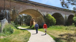 Shared use path alongside the Mulwarre river in Goulburn that goes under the impressive brick arch bridge carrying the Sydney railway line, with the original 19th century bridge supports in the background. This is proposed to be the start of the rail trail
