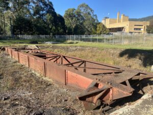 The remains of turntable to turn around steam locomotives at the La La Sidings site with the old Sanitarium Factory in the background. Taken from the Yarra River Walk [2024]